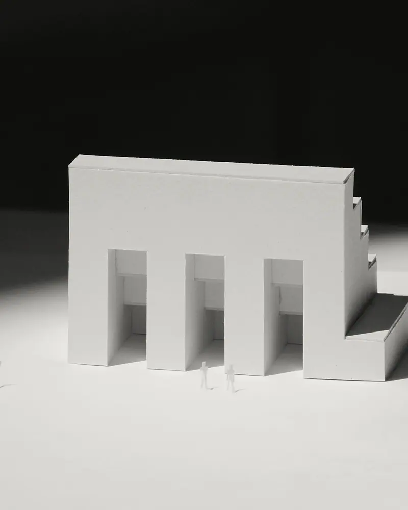 A mesma maquete branca iluminada lateralmente, projetando sombras longas.