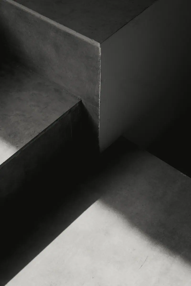 Escada de concreto em preto e branco com sombras fortes e geométricas.