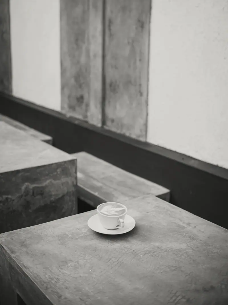 Xícara de café sobre bancos de concreto escalonados, em preto e branco.